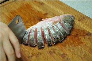 將鱸魚清洗干凈，從脊椎處切斷至腹部，腹部保留1cm左右不要切斷。