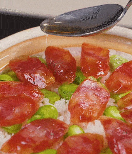 大米出現(xiàn)小孔時(shí)開蓋放香腸，往鍋邊淋入少許油，再燜煮8~10分鐘左右。