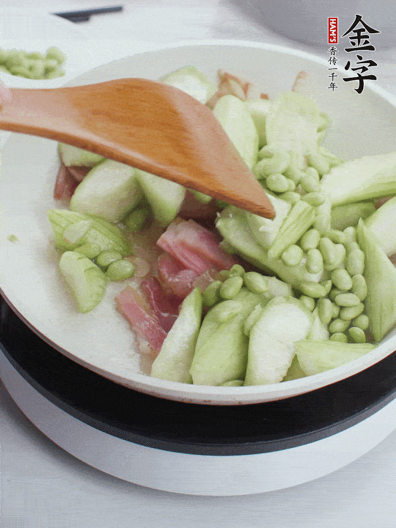 依次下絲瓜、青豆翻炒，炒至絲瓜打蔫縮小。