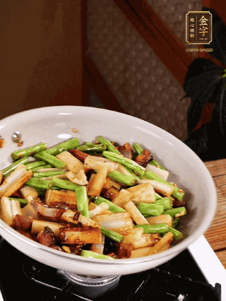油熱下蒜末、干辣椒、醬肉煸炒出香味，依次下藕條、豆角翻炒均勻